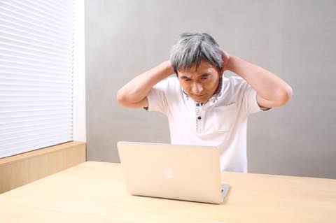 GATAG [フリー写真] パソコンの前で頭を抱えるシニア男性